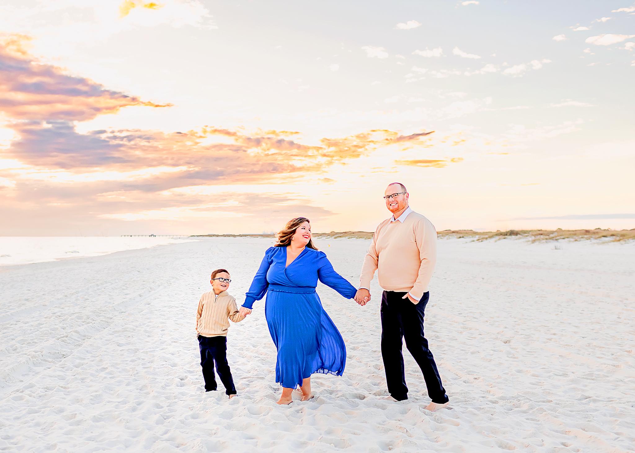 family walking along the sand in Orange beach cansisly posing for photographer