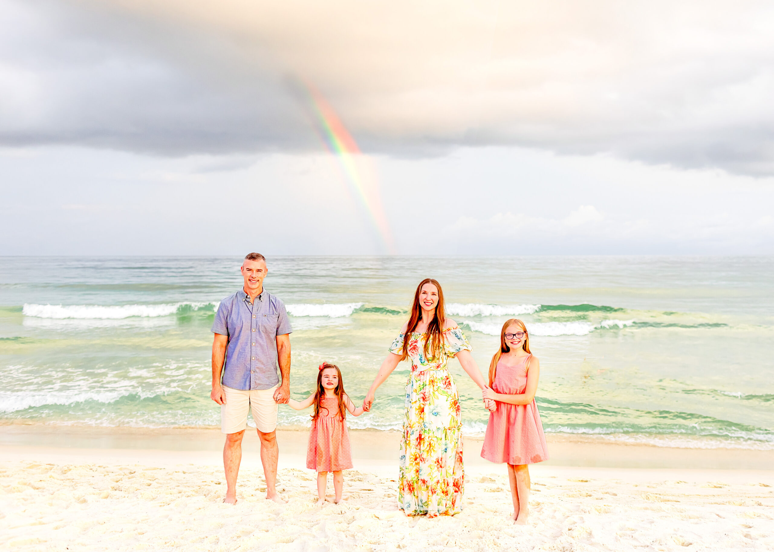 Epic family captured on the beach in front of a rainbow