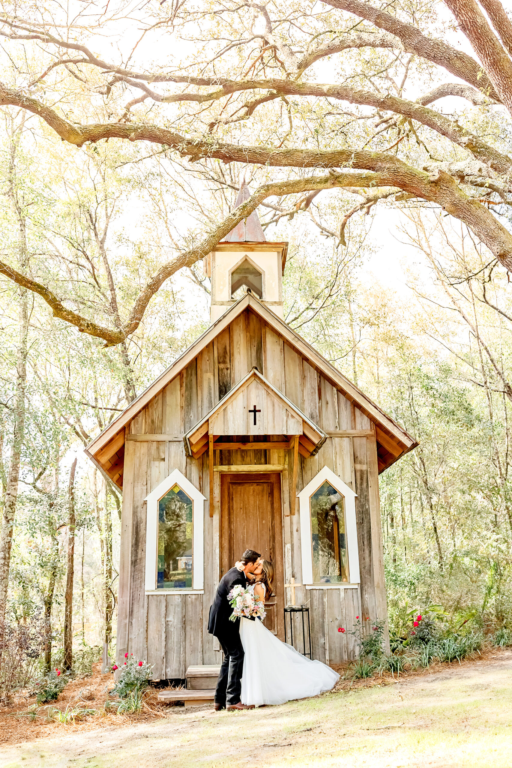 bride and groom kiss in front of chapel captured by fairhope wedding photographer